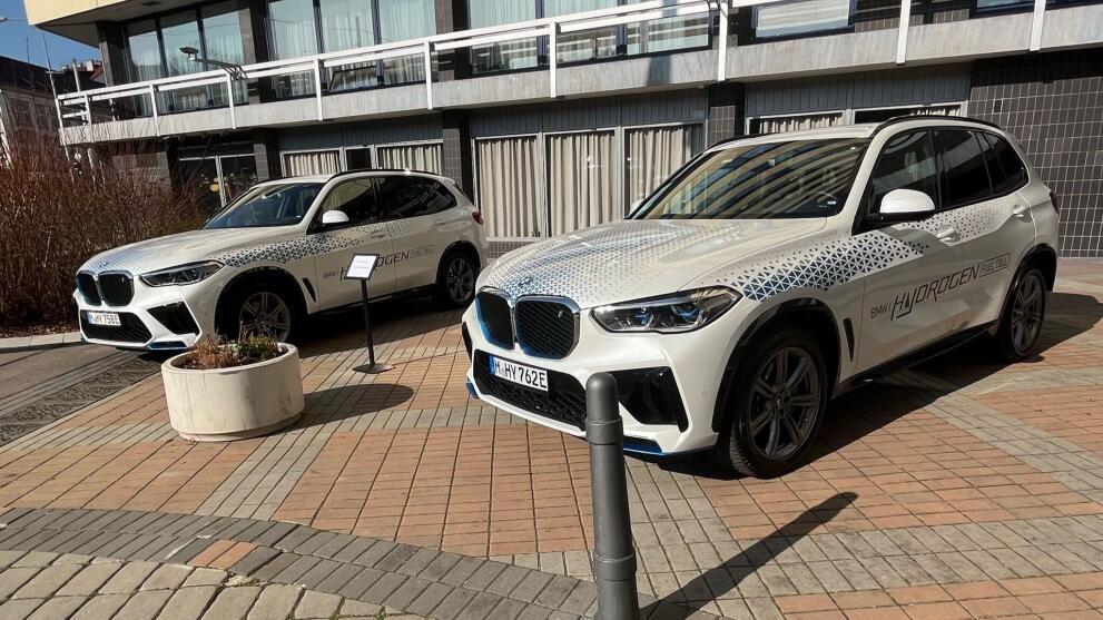 Two white BMWs in front of an exhibition hall