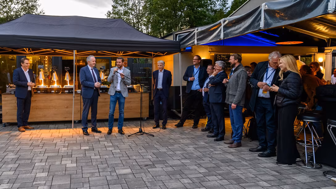 Eventlocation Torfgrube 4 außen. Mehrere Personen, eine spricht in ein Mikrofon.