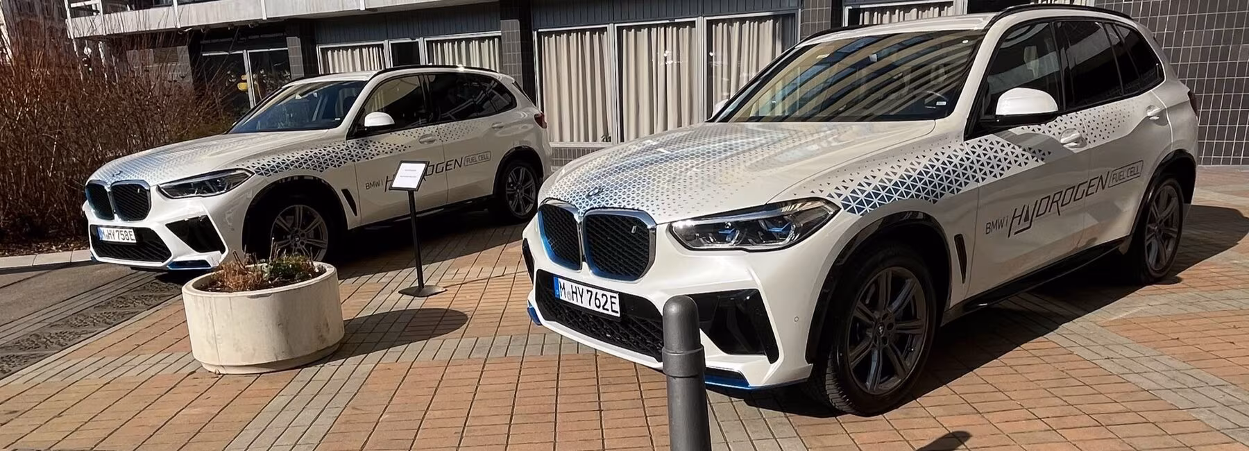 Two white BMWs in front of an exhibition hall