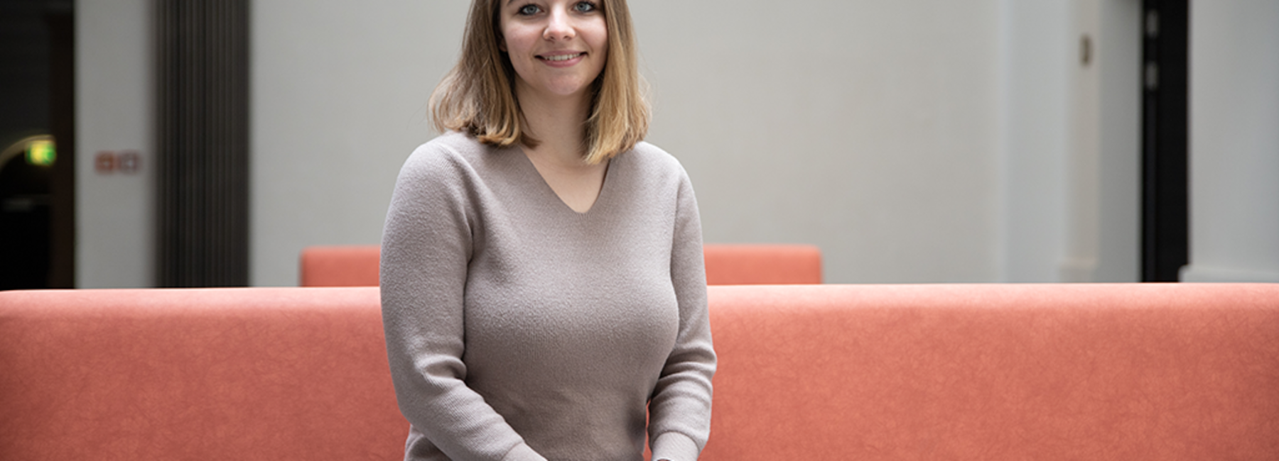 Alexandra Dutsch sitzt auf einem Sofa im Lichthof der Hochschule Mittweida und schaut in die Kamera.