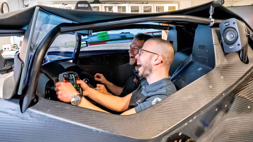 Zwei junge Männer, ausgelassen lachend, im Cockpit der Simulationsplattform.