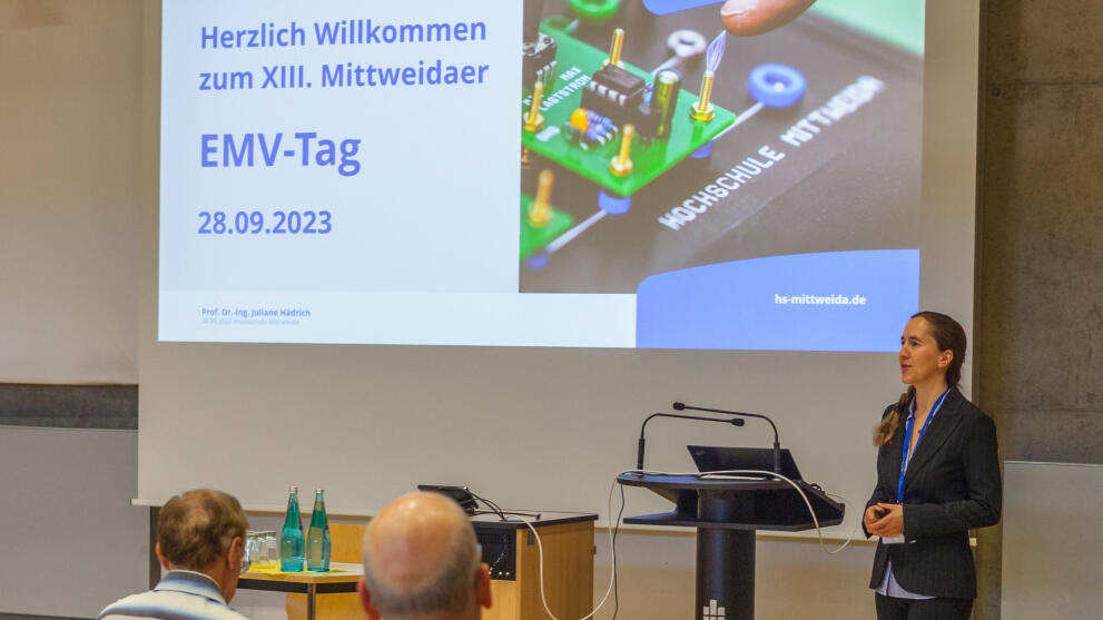 Weibliche Person steht vor Präsentationsfolie