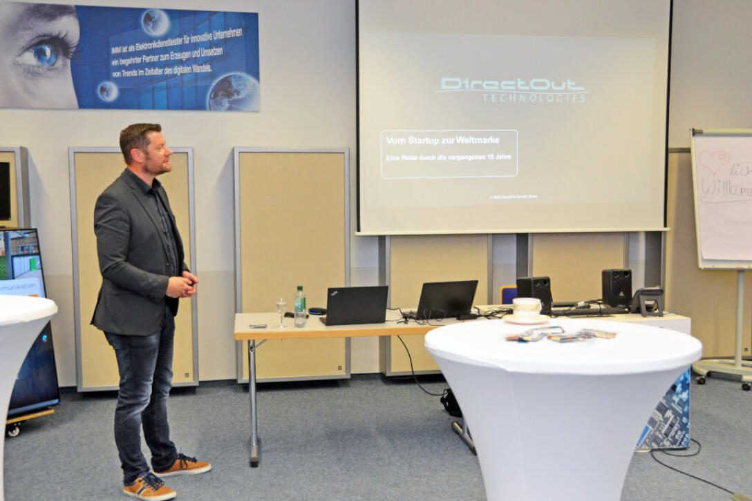 eine Person steht im Raum und präsentiert den Vortrag auf der Leinwand