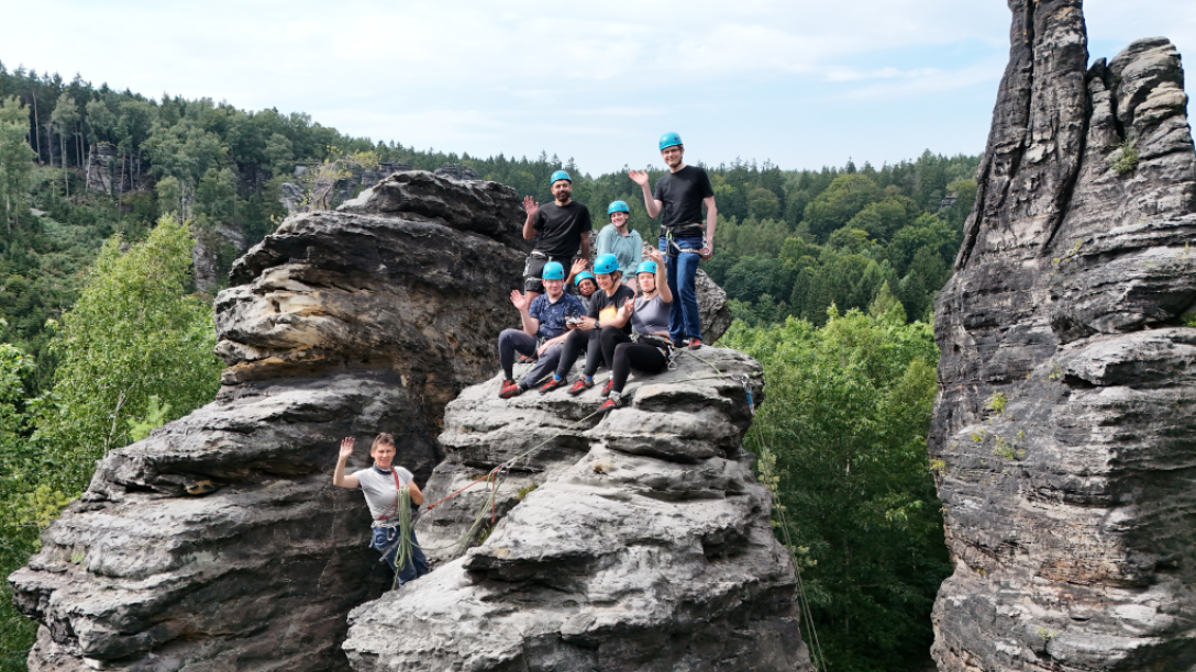 Gruppe von Personen mit Hlemen und an Kletterseilen auf Felsen