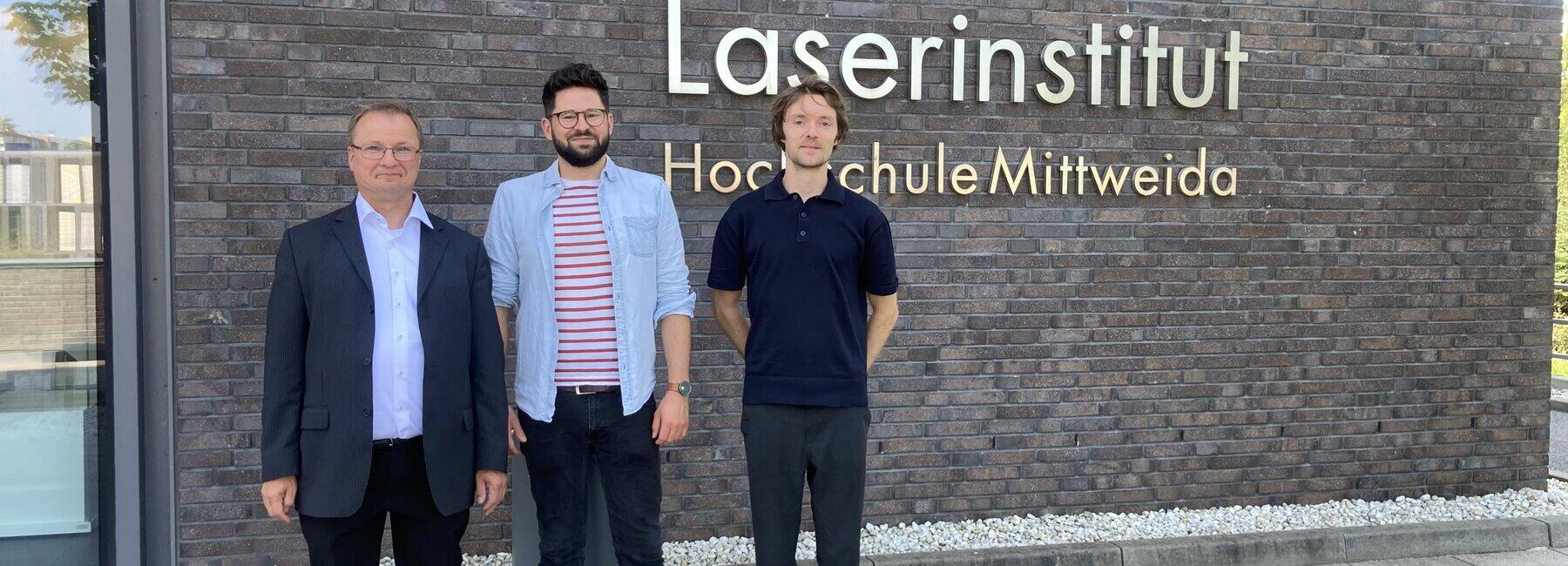 Drei Männer stehen vor einem Gebäude