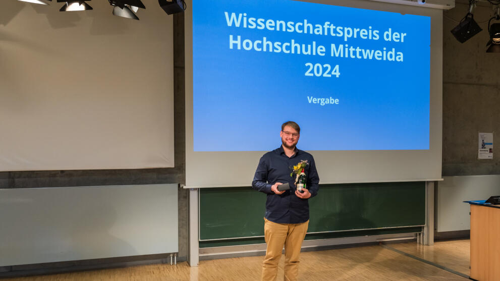 Männliche Person steht mit Preis vor einer Projektorwand
