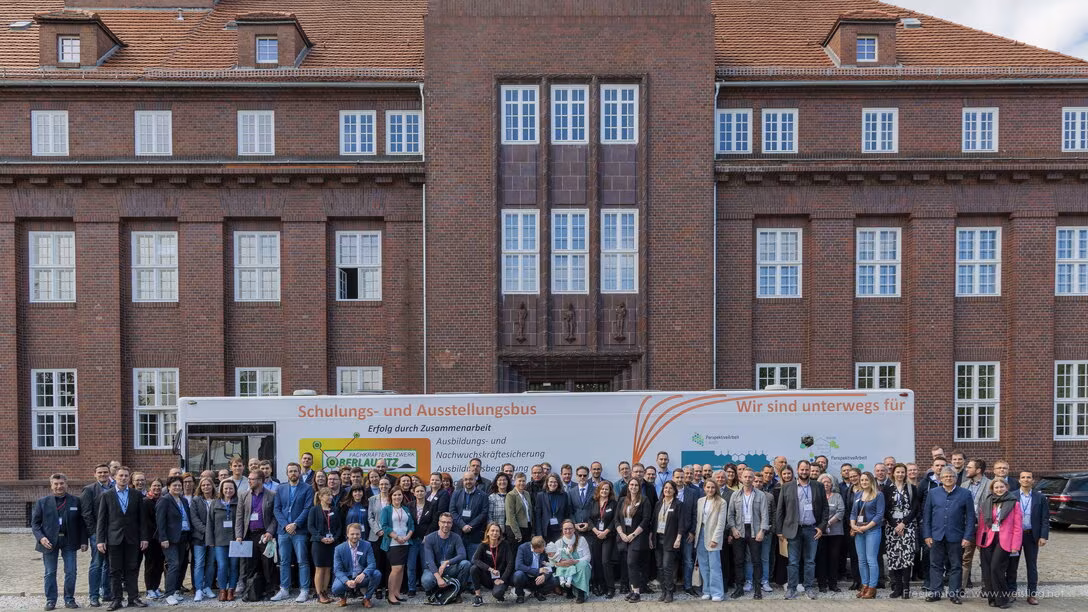 Gruppenbild vor einem verklinkerten Gebäude und einem Bus