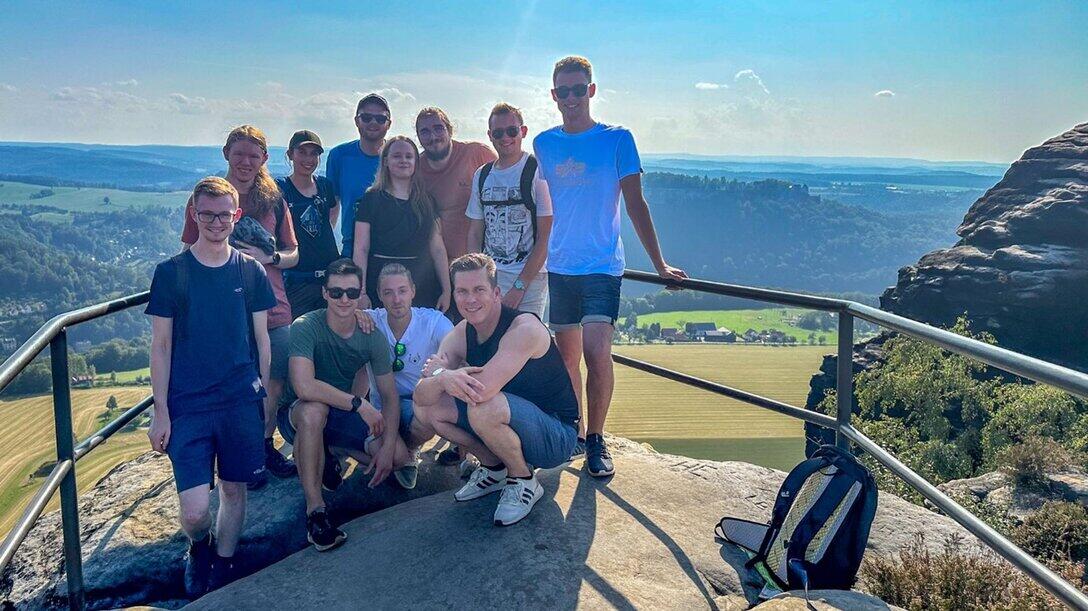 Wandergruppe steht auf Felsplateau und schaut in die Kamera