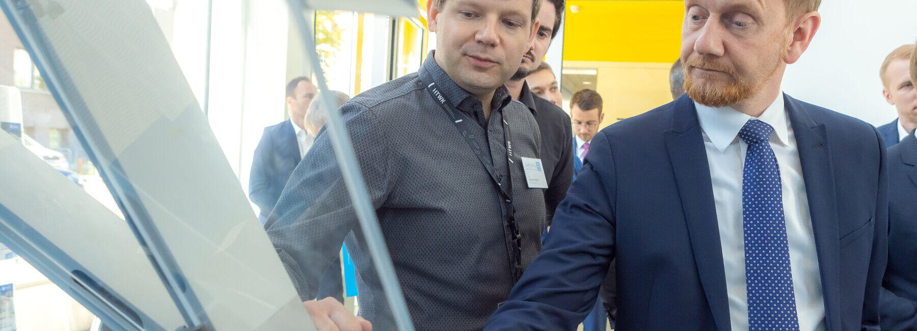 Zwei männliche Personen stehen vor einem Bauteil im Gespräch