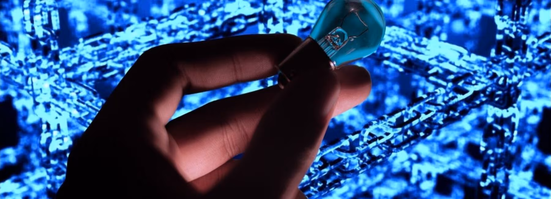A hand is holding a light bulb against a network-like background
