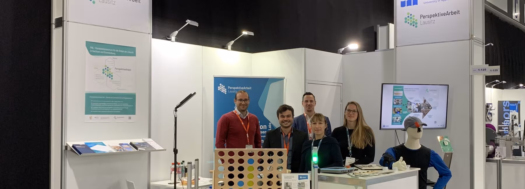 Fünf Personen stehen an einem Messestand