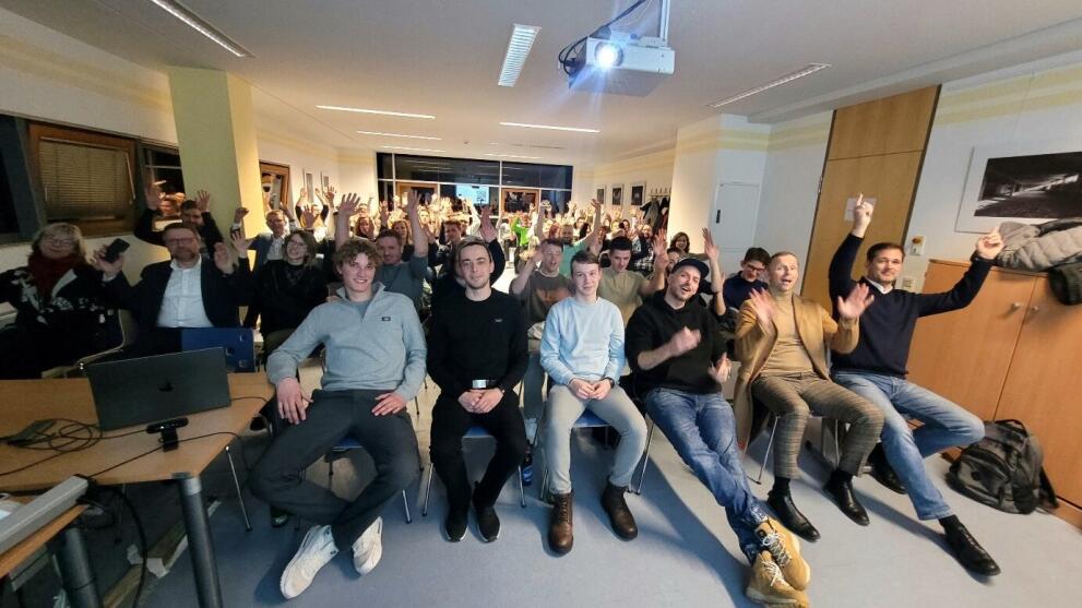 Menschen sitzen auf Stühlen und schauen in die Kamera