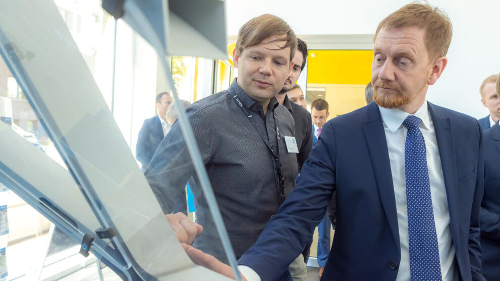 Zwei männliche Personen stehen vor einem Bauteil im Gespräch