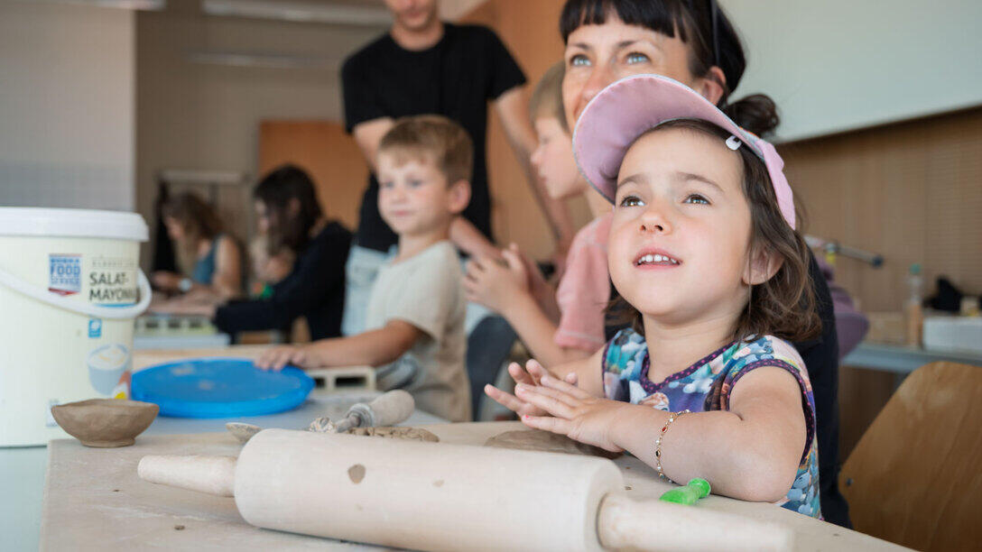Eine Erwachsene und mehrere Kinder, die an einem Tisch Knete bearbeiten.