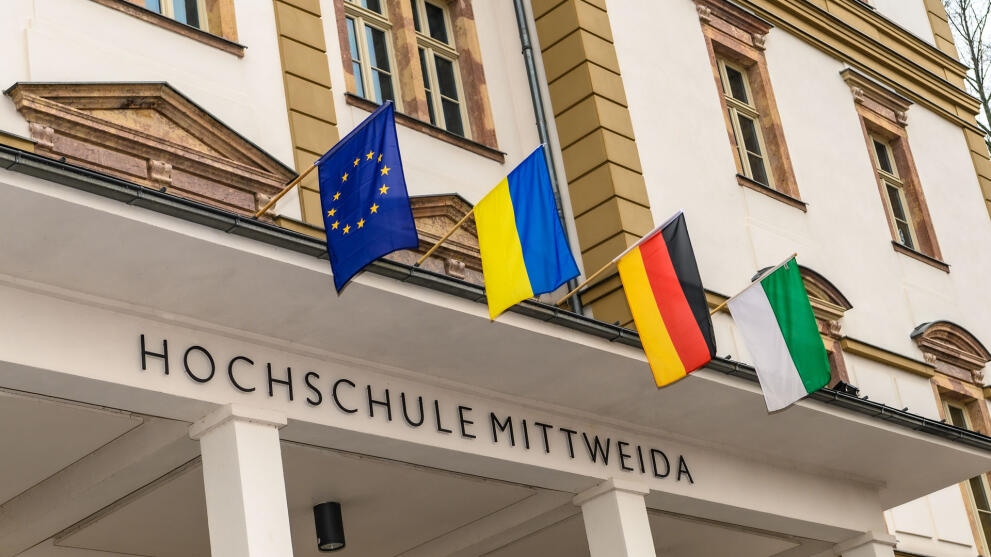 Am Hauptgebäude der Hochschule Mittweida sind über dem Eingang von links nach rechts die Flaggen der Europäischen Union, der Ukraine, Deutschlands und Sachsens gehisst.