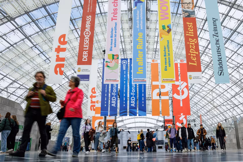 Blick in messehalle mit Menschen und bunten Bannern